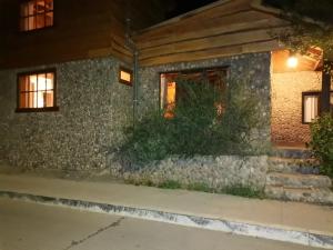 a house with a stone wall and a window at Calafates y lavandas in Chile Chico