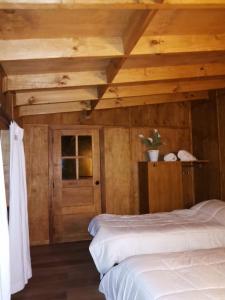 1 dormitorio con 2 camas y techo de madera en Calafates y lavandas en Chile Chico