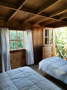 1 dormitorio con 2 camas y ventana en Calafates y lavandas en Chile Chico