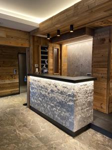 a lobby with a stone counter with wooden walls at Hotel Ariston ***S in Madonna di Campiglio