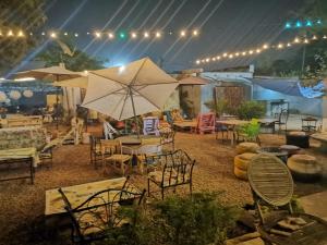 eine Terrasse mit Tischen, Stühlen und einem Sonnenschirm in der Unterkunft Villa Tenko in Ouagadougou