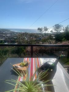 a glass balcony with a table and a plant on it at Panoramata @ Caves Beach in Caves Beach
