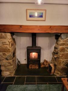 a wood stove in a room with a stone wall at 5 Goonbell in St. Agnes 