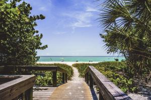 a wooden pathway leading to a beach with the ocean at Tropical Villas Of Venice Beach in Venice