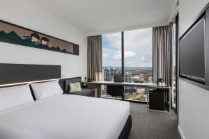 a hotel room with a bed and a large window at ibis Adelaide in Adelaide