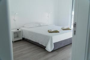 ポンタ・デルガダにあるSweet Ponta Delgadaの白いベッド(タオル2枚付)が備わるベッドルームです。