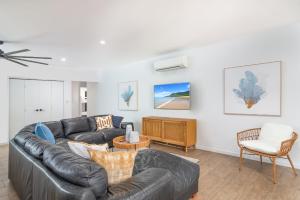 a living room with a leather couch and a tv at Paradiso in Port Douglas