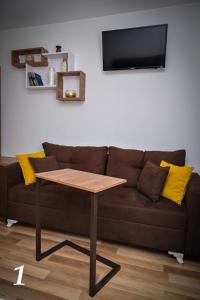 ein Wohnzimmer mit einem braunen Sofa und einem Tisch in der Unterkunft Studio apartmani Emili Bijeljina apartman br 1 in Bijeljina