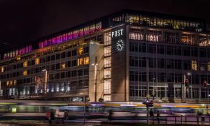 莱比锡Staycity Aparthotels Leipzig City Centre的一座大建筑,晚上有钟