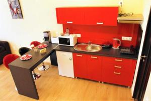 a small kitchen with red cabinets and a sink at Tribunei Apartment Sibiu in Sibiu