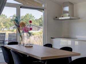 a dining room table with a vase of flowers on it at Beautiful chalet with a bath, in a holiday park in the Brabant Kempen in Veldhoven