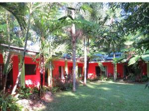 a red house with palm trees in front of it at Daintree Rainforest Retreat Motel in Cape Tribulation