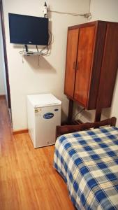 a room with a bed and a cabinet and a television at Plaza Hotel Fray Bentos in Fray Bentos