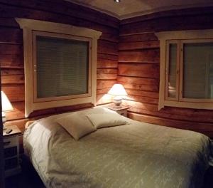 a bedroom with wooden walls and a bed with two windows at Villa Nangu in Inari