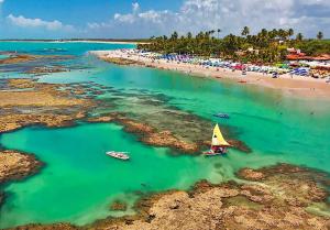 an aerial view of a beach with boats in the water at Casa de condomínio para 6 pessoas, tudo a pé, perto do centro e piscinas naturais in Porto De Galinhas