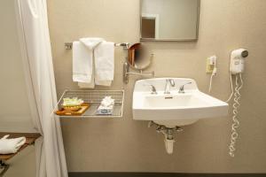 a bathroom with a sink and a phone on the wall at Hilltop Inn & Suites - North Stonington in North Stonington