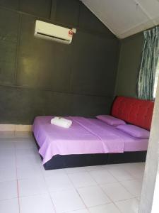 Un pequeño dormitorio con una cama morada en una habitación en Durian Chalet en Kuala Tahan