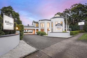 une grande maison blanche avec un panneau devant elle dans l'établissement Killara Hotel & Suites, à Killara