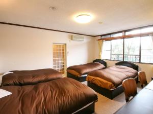 a bedroom with two beds and a window at Pension Kinrinko Toyonokuni in Yufuin