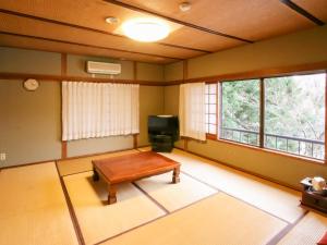 een woonkamer met een tafel en een televisie bij Pension Kinrinko Toyonokuni in Yufu