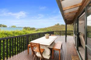 a deck with a table and chairs and a view of the water at Brind Lodge - Russell Holiday Home in Russell