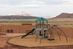 a playground with a wooden bench and a large rock at Gooseberry Lodges Zion National Park Area in Apple Valley