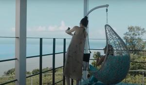 Una donna con un vestito seduto su un'altalena di GLORY ISLAND OKINAWA Yabusachi Resort a Nanjo