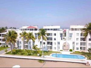 a large white building with a swimming pool and palm trees at Penthouse Ave Paraiso en Manzanillo 505 Apt 16b in Manzanillo