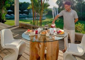 a man standing next to a table with food on it at Pure Villa Bali by Nagisa Bali in Dalung
