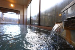 a pool with a water fountain in a building at Hotel Yamabuki in Komagane