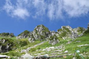 a mountain with rocks and grass and a blue sky at Hotel Yamabuki in Komagane