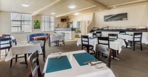 Caravilla Motor Inn في تاري: غرفة طعام مع طاولات وكراسي بيضاء