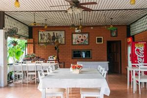 un restaurante con mesas y sillas blancas y ventilador de techo en Banviewnam Camping & Resort, en Bān Tha Pu Deang