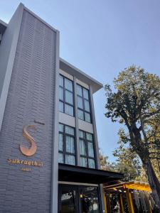 um edifício com um sinal na lateral em Sukruethai Hotel Chiang Mai - โรงแรมสุขฤทัย เชียงใหม่ em Chiang Mai