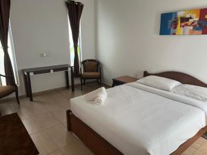 a bedroom with a large white bed and a desk at Hujung Kampung Estate in Pantai Cenang