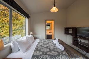 a bedroom with a bed and a flat screen tv at Pinewood Lodge and Apartments in Queenstown