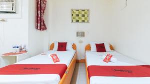 2 camas en una habitación con sábanas rojas y blancas en RedDoorz @ Eros Travellers Pensione, en Iloilo City