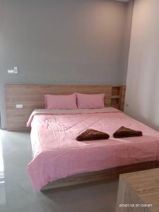 um quarto com uma cama rosa e 2 almofadas castanhas em The S อพาร์ทเม้นท์ em Ban Pra Dok