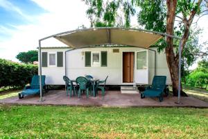 a house with a patio with chairs and a table at Village & Camping La Foce in Valledoria