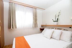 a hotel room with a white bed and white comforter at Village & Camping La Foce in Valledoria