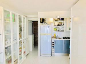 cocina blanca con nevera y armarios en Investingspain Studio beach paradise front sea views swimming pool, en Platja d'Aro