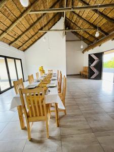 a long dining room with wooden tables and chairs at Hinterland Lodge in Ulundi