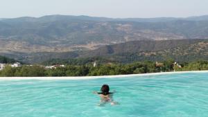 Eine Frau schwimmt in einem Pool mit Bergen im Hintergrund in der Unterkunft Finca El Chaparral in Cortelazor