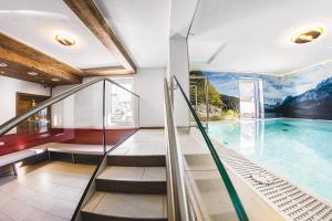 kryty basen ze schodami ruchomymi i dużym oknem w obiekcie Wellness- und Familienhotel Dachsteinresort w mieście Rußbach am Paß Gschütt