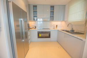 a kitchen with white cabinets and a stainless steel refrigerator at Al Aqah Luxury Apartment w/ Sea Views at Address Residences in Fujairah