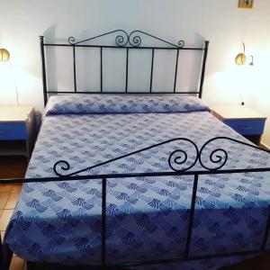 a bed with a blue comforter on it with two tables at La Casa di Anna in Lampedusa +28 photos