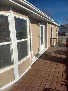 a house with a wooden deck with windows at Curt's cozy room rentals in Wendover
