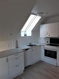 uma cozinha com armários brancos, um lavatório e uma clarabóia em Nabo til domkirken em Viborg