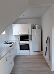uma cozinha com armários brancos e um frigorífico branco em Nabo til domkirken em Viborg