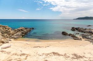 a beach with rocks and the ocean with a boat on it at Almare Seaside Studios & Suites - Sarti Sithonia in Sarti